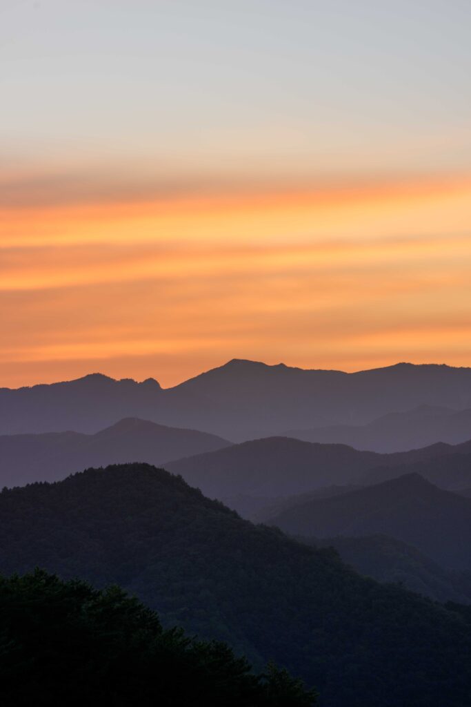 超望遠レンズで朝日に染まる山岳地帯を切り取った写真。マジックアワーによる色のグラデーションが綺麗。